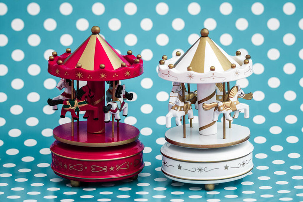 Vintage wooden carousel horses on a blue background with white polka dots, two carousel models with red and white striped roofs, generated with AI. - Photo, Image