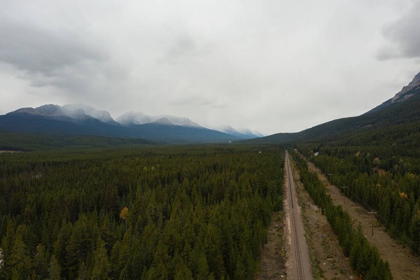 Luftaufnahme der Bahngleise, die die kanadischen Rocky Mountains überqueren, umgeben von Bäumen. - Foto, Bild