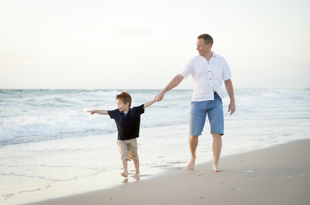 boldog apa fogta a gazdaság kezét kicsi fia, gyaloglás együtt a strandon, mezítláb - Fotó, kép