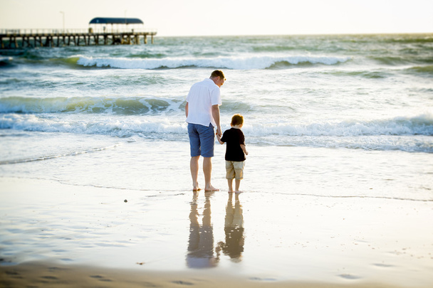 Šťastný otec hospodářství ruku malého syna spolu chodit na pláži s naboso - Fotografie, Obrázek