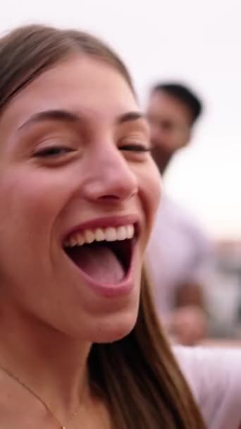 POV vertikales Video attraktive kaukasische junge Frau, die kokett in die Kamera schaut. Tanzen und mit Rotweinglas anstoßen. Gruppenfreunde feiern gemeinsam auf einer Dachparty. Junges Mädchen flirtet - Filmmaterial, Video