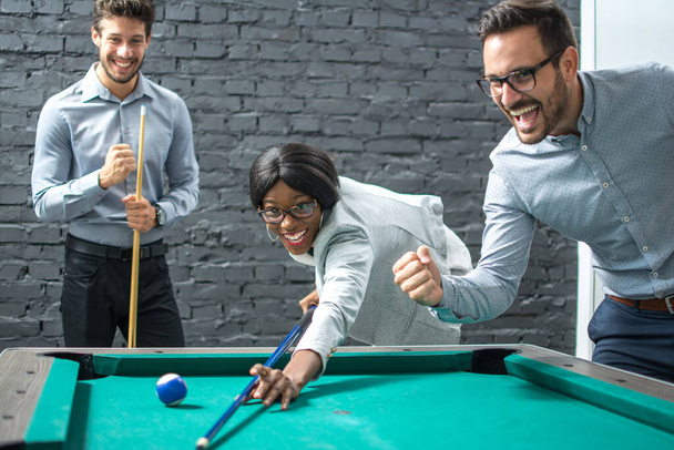 Cheerful business people playing billiards during office break. - Photo, Image