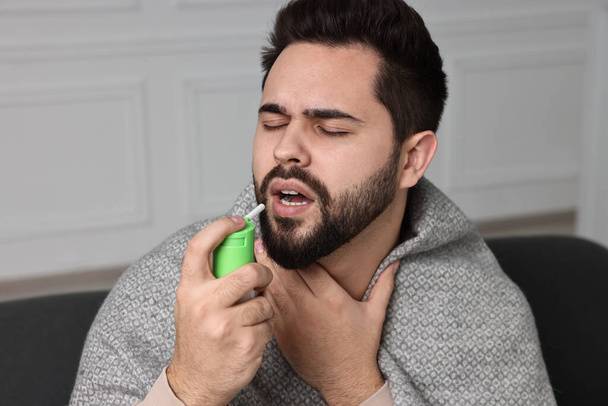 Young man using throat spray at home - Photo, Image