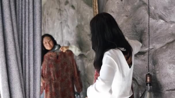 mooi jong aziatisch vrouw getting gekleed op zoek in spiegel kiezen outfit mode keuze zetten op kleding genieten positief zelfbeeld gevoel zelfvertrouwen thuis  - Video