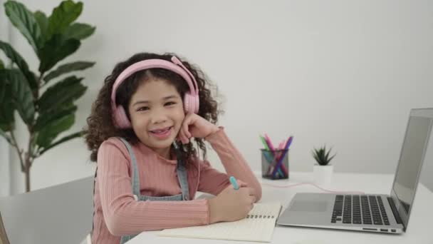 Pohled na chytré děvče, jak si sundává sluchátka a dělá domácí úkoly v samostudiu. Kavkazské školačky píšou na notebooku při hledání programovacího systému a psaní inženýrské výzvy. Pedagogika. - Záběry, video
