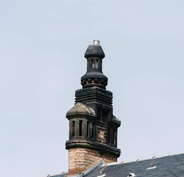 Een gedetailleerde stenen schoorsteen staat trots op een dak in Haguenau, Alsace, markeert de regio 's tijdloze architectuur tegen een achtergrond van heldere hemel - Foto, afbeelding