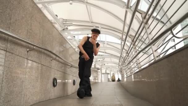 Umiejętny przystojny hipster wykonuje taniec uliczny w wąskim korytarzu. Profesjonalny hip hop tancerz pokazać b-boy krok na korytarzu w mieście, nosząc stylowe tkaniny. Sport na świeżym powietrzu 2024. Sprytnie. - Materiał filmowy, wideo