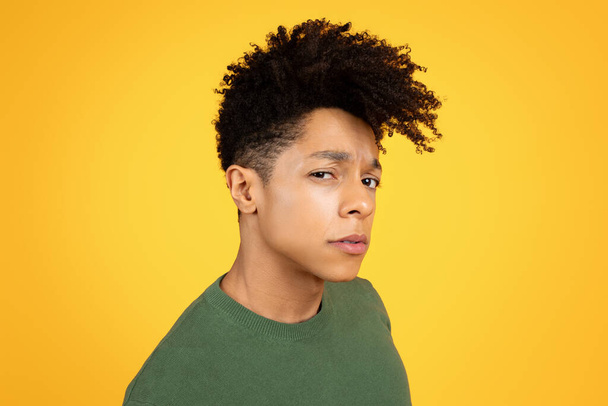 Close-up portrait of a young black man with a contemplative expression on a yellow background - Photo, Image