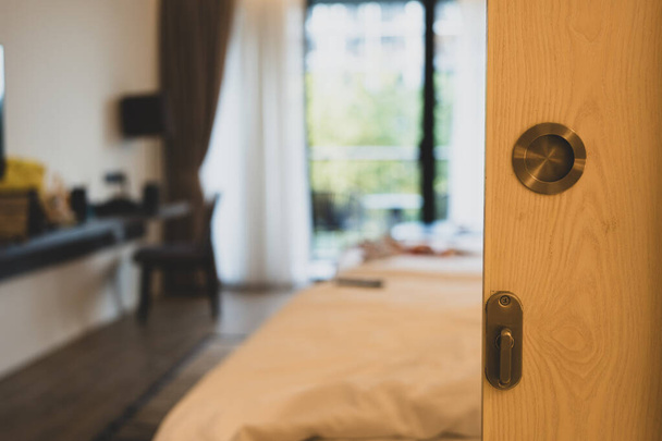 Blick durch die Holztür in ein Schlafzimmer mit zwei Doppelbetten und Fenstern. Stilvolles Zimmer durch offene Tür - Foto, Bild