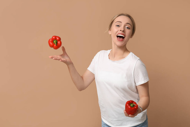 Young woman with bell peppers on beige background - Photo, Image