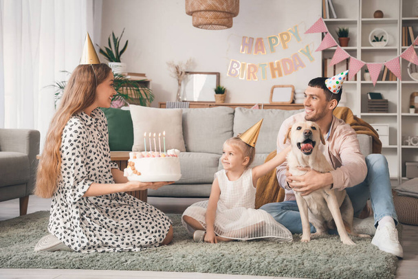 Gelukkige familie met taart en Labrador hond vieren verjaardag thuis - Foto, afbeelding