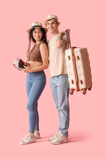 Couple of tourists with suitcase and passports on pink background - Foto, immagini