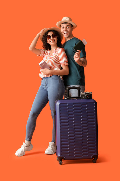 Couple of tourists with suitcase and passports on orange background - Photo, Image