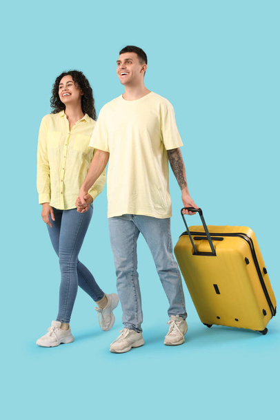 Couple of tourists with suitcase walking on blue background - Photo, Image