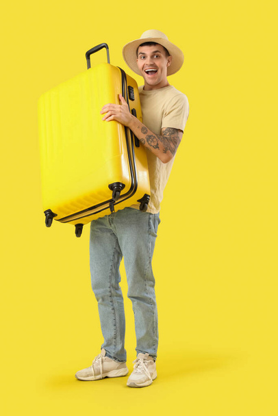 Fiatal férfi turista bőrönddel sárga alapon - Fotó, kép