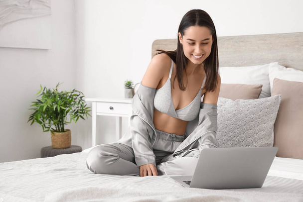 Sexy young woman with laptop in bedroom - Photo, Image