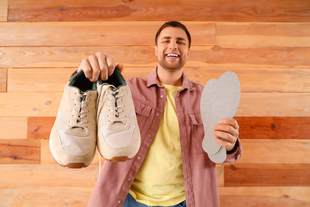 Мужской сапожник с кроссовками и стельками на деревянном фоне - Фото, изображение