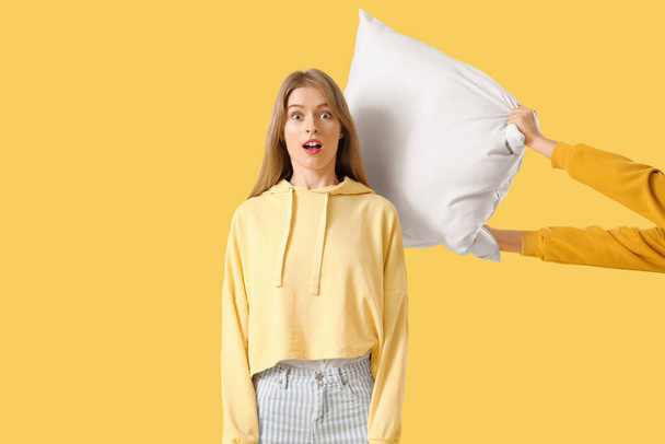 chocado jovem mulher chegando bateu com travesseiro no amarelo fundo - Foto, Imagem