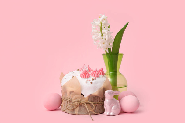 Heerlijke paastaart, beschilderde eieren, konijn en hyacint in vaas op roze achtergrond - Foto, afbeelding