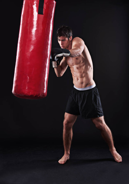 Человек, перчатки и боксерская сумка для тренировки или кардио тренировки для здоровья, боец или черный фон. Мужчина, перфоманс и боевые искусства обучение в студии на макете для фитнеса, тренажерный зал или кулак. - Фото, изображение