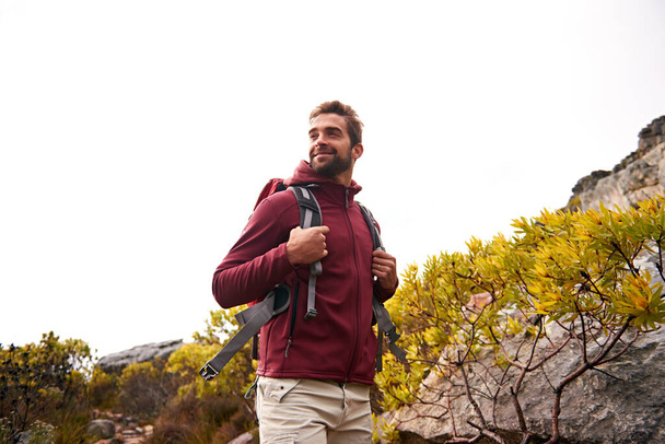 Happy, man and hiking with backpack on mountain for travel, adventure and fitness. Male person, smile and tourist, camping, exercise and trekking countryside or forest outdoors for sightseeing. - Photo, Image