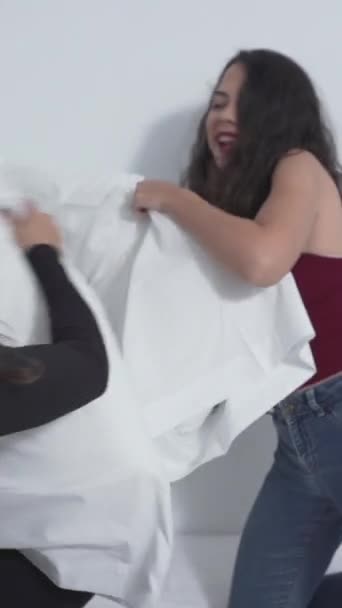 Twee Colombiaanse vrienden die een kussengevecht hebben in bed. - middelgroot schot - verticaal 1080 - Video