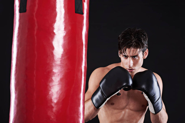 Fitness, boxing or man with punching bag in studio for exercise, challenge or competition training. Power, muscle or champion boxer at workout with confidence, martial arts fight and black background. - Photo, Image