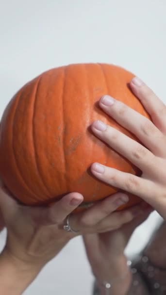 Mladé dívky v kostýmu čarodějnice drží a tření dýně během Halloweenu. - zblízka - svisle 1080 - Záběry, video