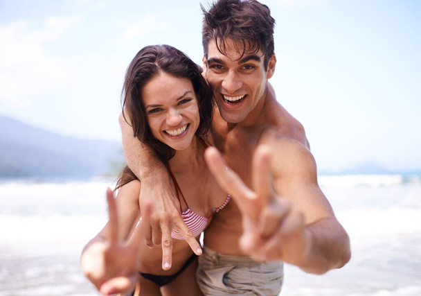 Liebe, Frieden und Porträt eines Paares am Strand für tropische Urlaubsabenteuer, Entspannung oder Zusammenhalt. Natur, glücklicher Mann und Frau bei romantischem Date mit Meer, blauem Himmel und Lächeln im Urlaub. - Foto, Bild