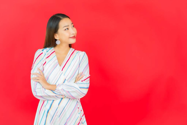 Ritratto bella giovane donna asiatica sorriso con molti azione su sfondo rosso - Foto, immagini