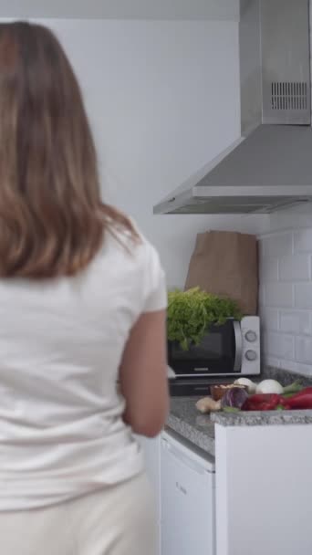 Nuori nainen ottaa veitsellä ja leikkuulauta keittiön laatikosta. - laajakuva - Pystysuora - Materiaali, video