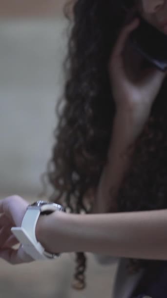 Menina falando em Smartphone olhando para seu relógio de pulso. Close-up - Vertical - Filmagem, Vídeo