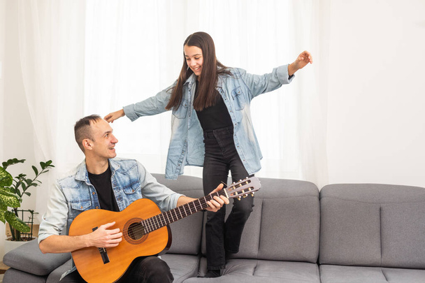 Otec učí holku hrát doma na kytaru. Rodinné hudební lekce se smyčcovými nástroji. Kvalitní fotografie - Fotografie, Obrázek