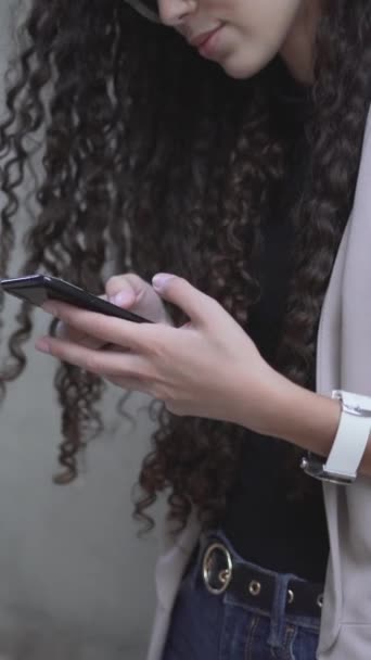 Curly-Haired Moroccan Lady Sorrindo Enquanto Olhando em seu Smartphone. Visão lateral - Vertical - Filmagem, Vídeo