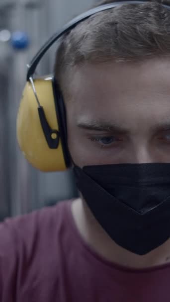 Καυκάσιος που δουλεύει σε εργοστάσιο μπύρας φορώντας ωτοασπίδες και μάσκα προσώπου. Close Up - Κατακόρυφο βίντεο FullHD - Πλάνα, βίντεο