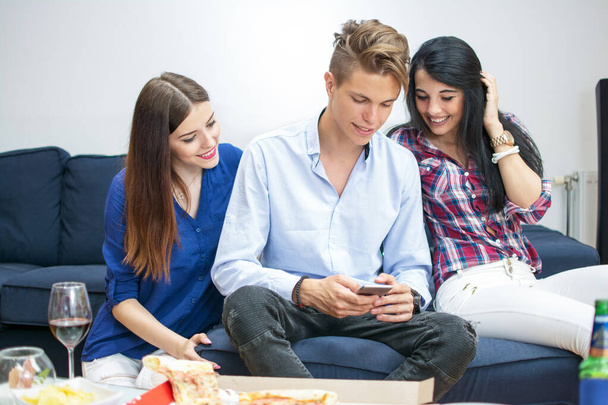 Троє молодих друзів використовують смартфон вдома - Фото, зображення