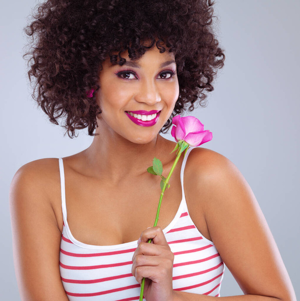 Portrait, beauty and black woman with flower in studio for skincare, floral cosmetics or dermatology on gray background. Lipstick, pink rose and female model for makeup, glowing skin and eyeshadow. - Photo, Image