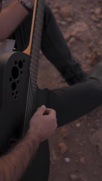 Fiatal férfi gitáros hipster szabadban gitározni top view közelkép ihlette naplemente - függőleges FullHD videó - Felvétel, videó