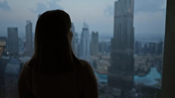 Silhouetted nainen näkymät valaistu Dubai horisonttiin korkean rakennuksen observatorion hämärässä. - Materiaali, video