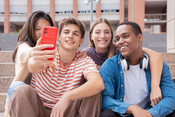 Eine fröhliche multiethnische Gruppe junger Freunde macht gemeinsam ein Selfie auf dem Campus. multirassische Studenten, die sich in der Stadt versammeln, Konzepte der Jugend, des Lebensstils der Menschen, der Diversität, des Teenager- und Stadtlebens - Foto, Bild