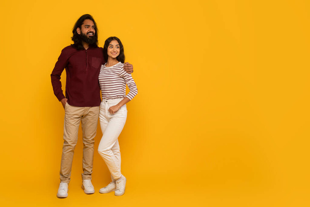 Mężczyzna i kobieta stoją plecami do siebie z skrzyżowanymi ramionami, emanując relaksującą atmosferą na żółtym tle - Zdjęcie, obraz