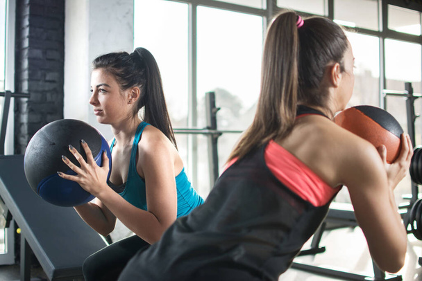 Sportlerinnen machen im Fitnessstudio Übungen mit Fitnessbällen - Foto, Bild