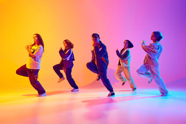 Tanssijat dynaamisessa liikkeessä, näyttää nykyajan hip-hop tanssityylejä neon valossa vastaan kaltevuus värikäs studio tausta. Harrastuksen, urheilun, muodin, toiminnan, nuorisokulttuurin, musiikin ja tanssin käsite. - Valokuva, kuva
