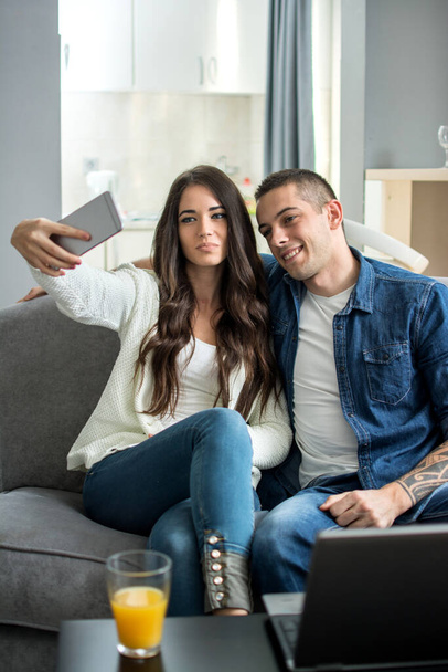 Young smiling couple taking selfie with smartphone at home - Photo, Image