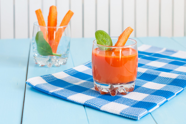 Gezonde zelfgemaakte wortelsap in glas en verse wortelen op lichte houten achtergrond. - Foto, afbeelding