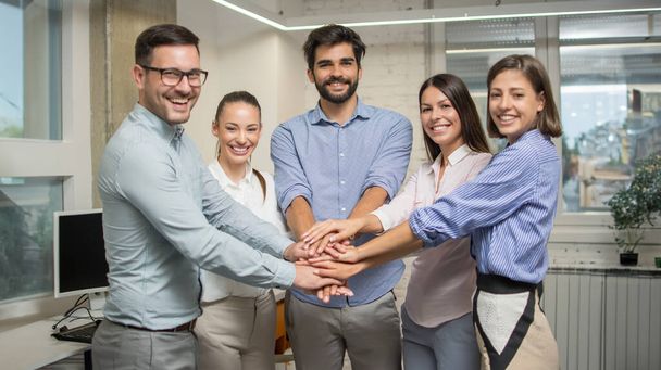Ryhmä yritysten työtoverit pinoavat kätensä yhteen osoittaa joukkueensa yhtenäisyyden toimistossa. - Valokuva, kuva