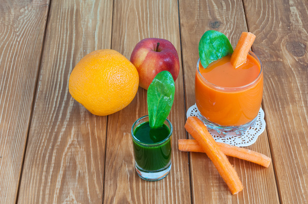 Здоровый домашний морковный сок в стакане и свежая морковь, шпинат на светлом деревянном фоне
. - Фото, изображение