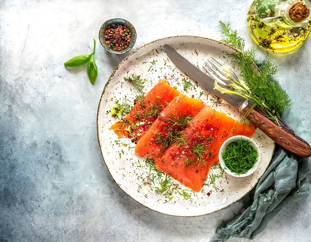 Top view of a plate of smoked salmon adorned with fresh dill, spices, and a drizzle of olive oil on a textured background. Gravlax - Photo, Image
