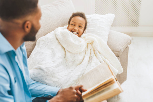 Padre leyendo cuento de hadas a la pequeña hija antes de dormir en el sofá
 - Foto, Imagen