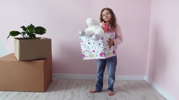 Malá holčička šťastně tančí u krabic s věcmi a raduje se ze svého nového domova. Nové bydlení. Nemovitosti a nájemní smlouvy, úvěry a hypotéky, koncept dne relokace. Zpomalený pohyb. - Záběry, video